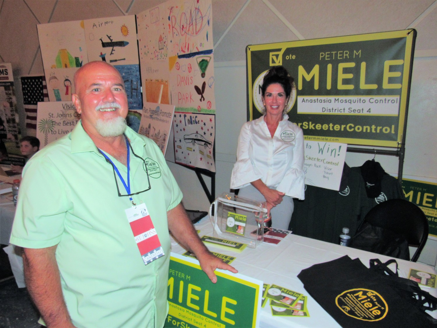 Peter Miele, who is running for the Anastasia Mosquito Control District 4 seat, poses by his table with supporter Cathlene Miner.